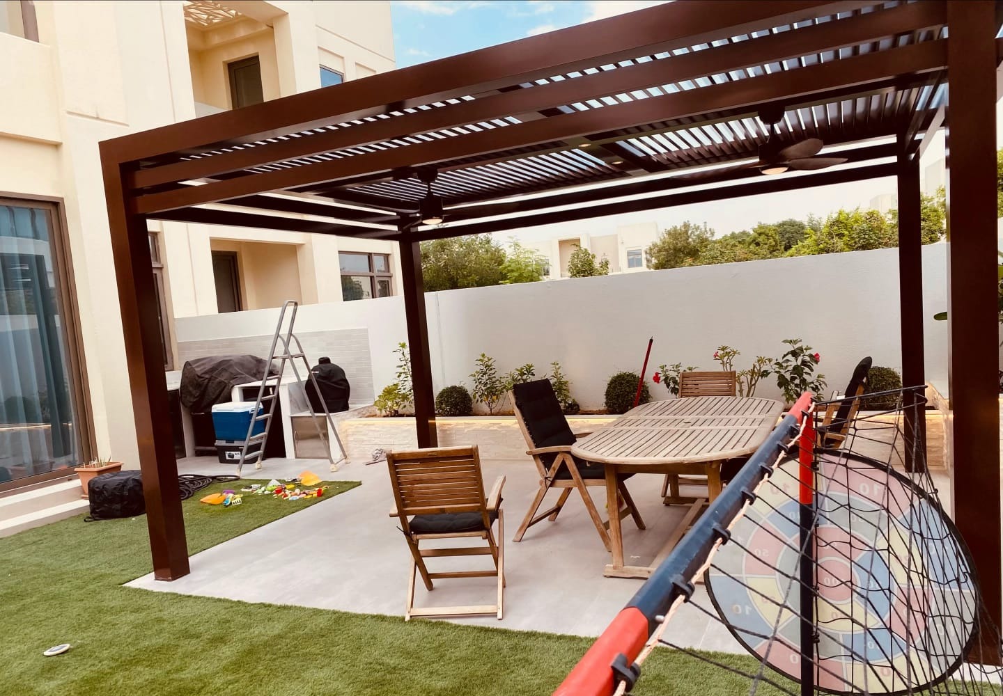 Finished aluminium pergola over an outdoor dining area, Dubai villa