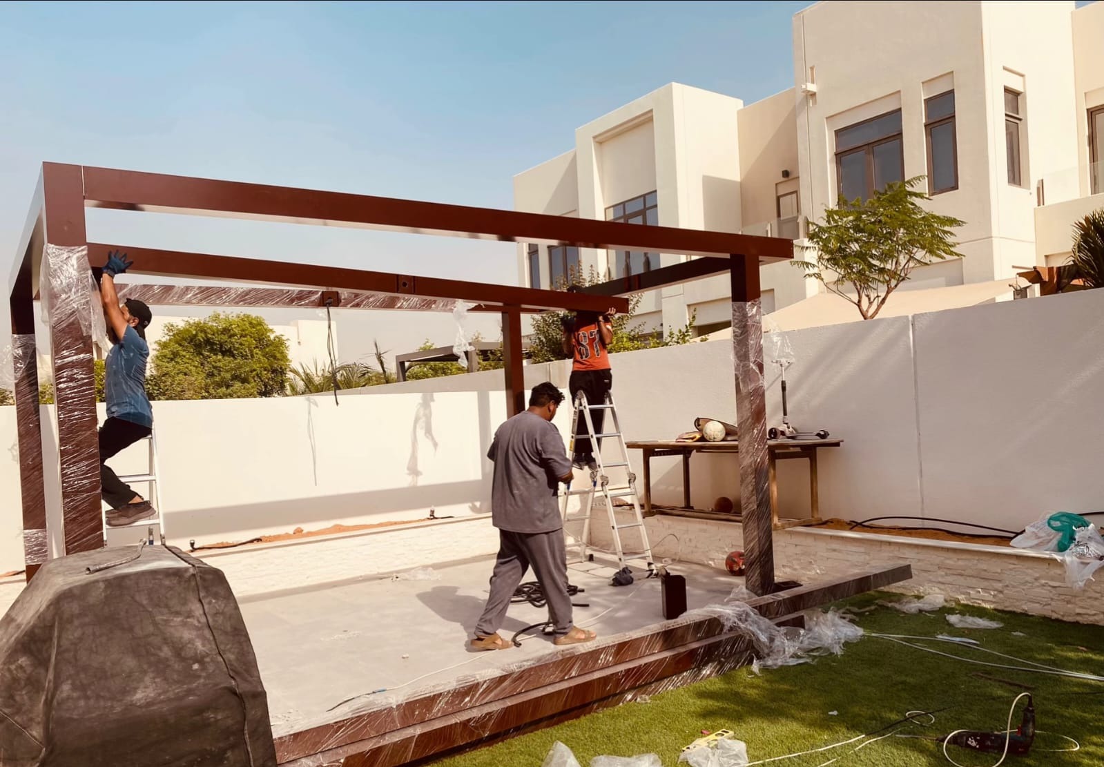 Crew installing an aluminium pergola frame in a Dubai backyard