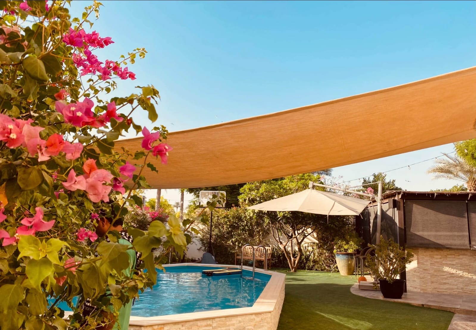 Stone-clad pool edge and planted garden corner, Dubai villa